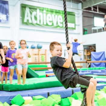 Child swinging on rope in gymnastics room